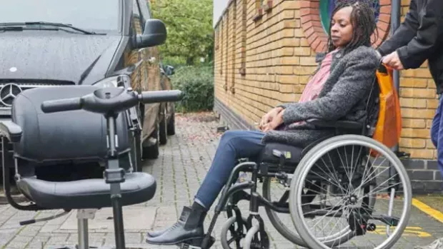 Woman in wheelchair next to a car