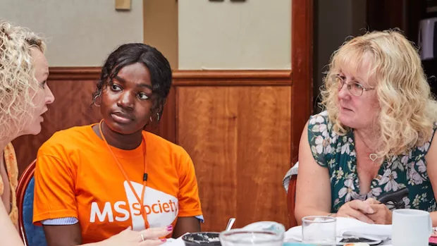 A group of people sitting round a table sharing their MS stories