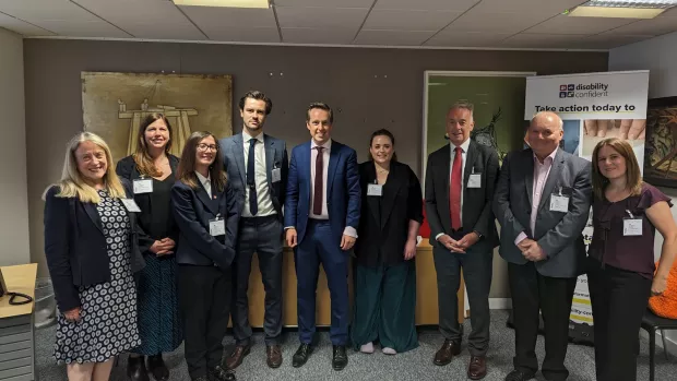 Tom Purseglove, MP, stands in an office flanked with representatives from leading UK MS charities