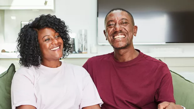 Simone and Nikoma are sat on an armchair in their home