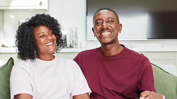 Nikoma and Simone on their sofa at home holding each other and smiling