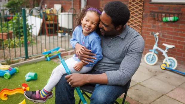 A man sitting outside, holding his daughter