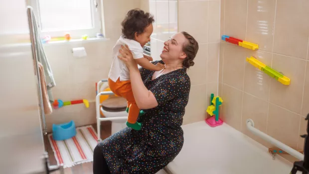 A woman lifts up her child in a bathroom