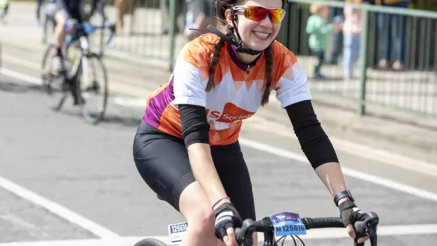 A cyclist smiles and wears an orange MS Society cycling shirt