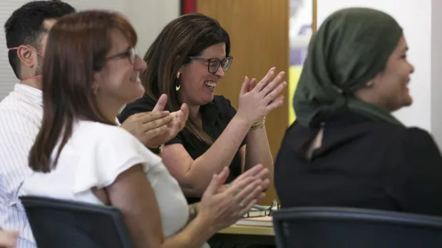 Members of the board of Trustees clapping at a meeting