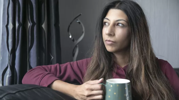  A person with MS holding a mug and looking out of the window