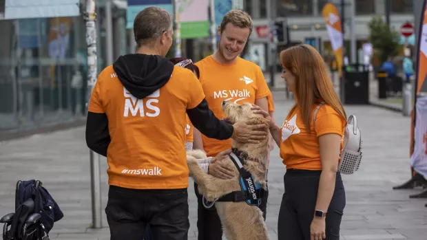 People in MS Walk t-shirts playing with a dog