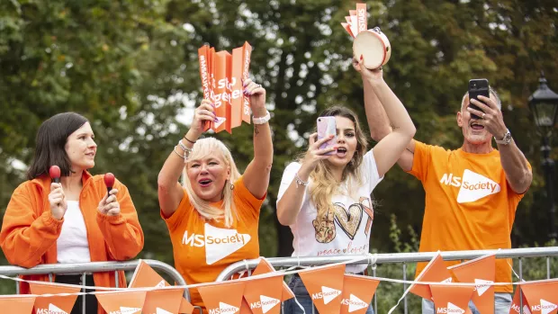 A group of supporters in MS Society t-shirts cheering at a fundraising event