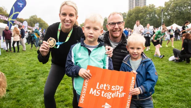 A family at a running event holding an MS Society poster