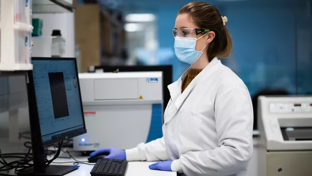 A researcher in a lab working on a laptop