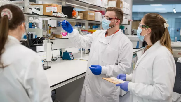 Three researchers discussing their work in a lab