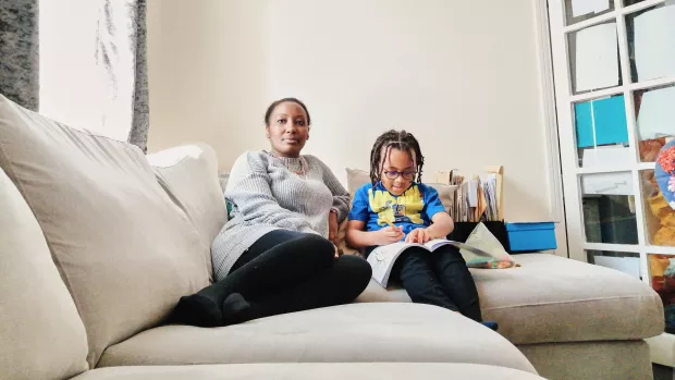 A woman sits on the sofa with her child