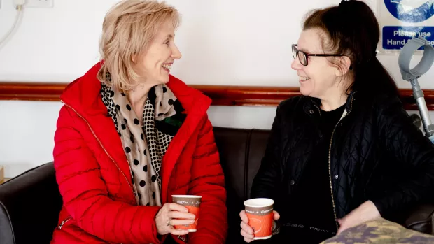 Two people holding coffee cups and smiling