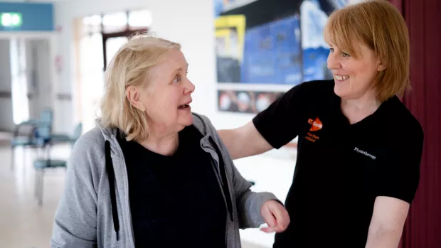 A person in an black MS Society t-shirt talks to a woman with MS