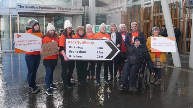  A group of MS Society campaigners holding placards for a PIP campaign