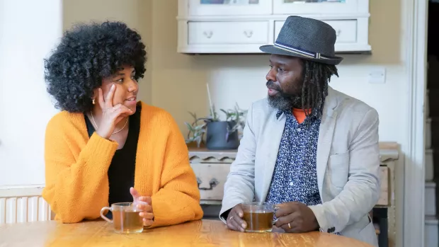 Two people sitting at a table having tea looking at each other