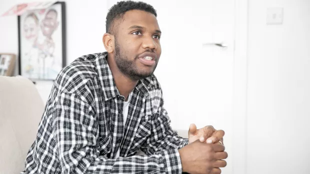  A man sitting on the sofa with his hands clasped