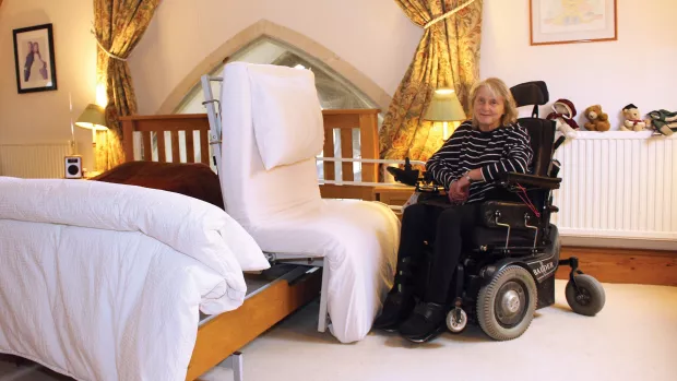 A woman in a wheelchair next to a Theraposture chair