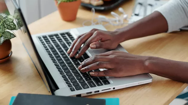 A close-up of hands typing on a laptop