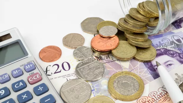 A selection of UK coins and banknotes next to a calculator