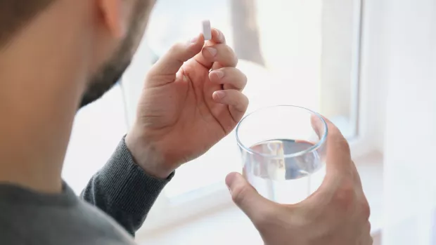 A man holding a tablet and a glass of water