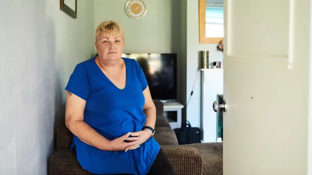 Person wearing a blue top sits in their living room