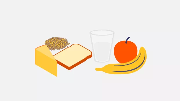 Arrangement of an apple, banana, bread, glass of milk and cheese