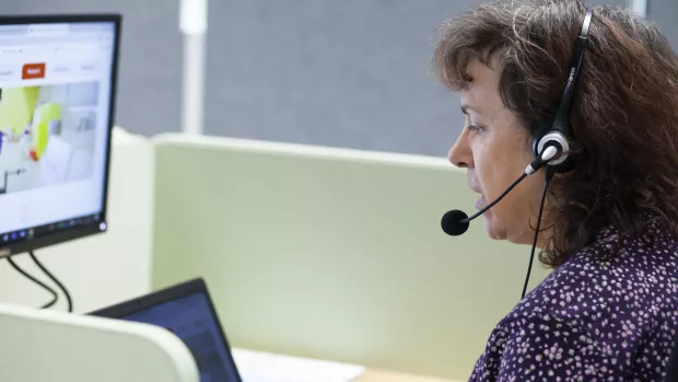 A person wearing a headset sits in front of a computer