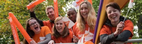 Photo shows a group of cheerers at an MS Society cheering station waving flags