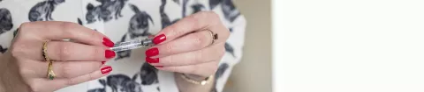 Photo: Kirsty's hands with red nails holding her MS treatment