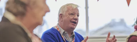 Man wearing blue jumper talking and gesticulating with his hands