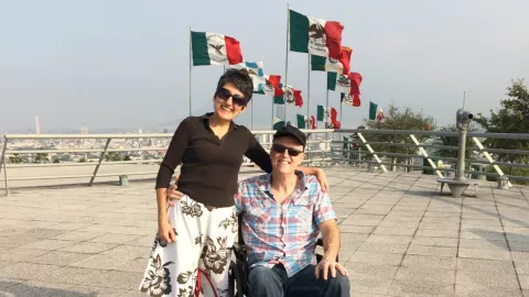 Miles and his wife in Mexico with Mexican flags in background