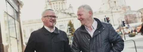 Two men chatting as they walk down the street in Belfast