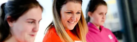 A smiling woman wearing an MS Society t-shirt, in a group.