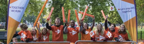 People wearing MS Society orange behind a barrier with banners cheering