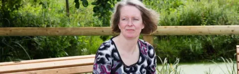 A woman staring into the distance on an outdoor bench, representing how MS can affect mental health.
