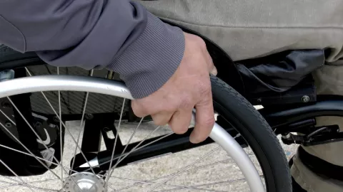 Photo: close up of person in wheelchair's hand on wheel rim
