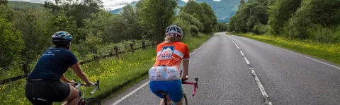Two cyclists cycling on a countryside road