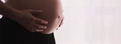 image shows a pregnant lady holding her bump