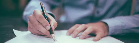 Man in shirt writing on a piece of paper