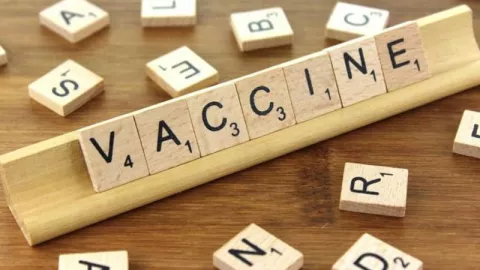 Wooden scrabble tiles in a tray spelling out vaccine