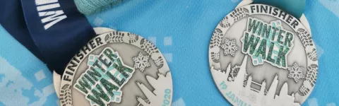 Two silver winter walk medals on a blue background