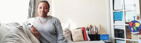 Rebbecca sits on her sofa looking to camera