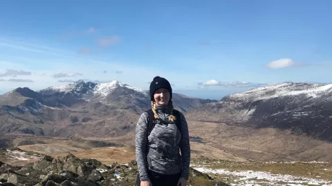Hannah standing on a mountain in the Lake District under a blue sky
