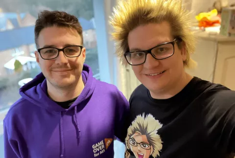 Photo of Mark and his boyfriend Mart. Mark is wearing a purple Game Over for MS hoodie.