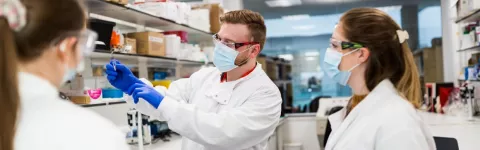 Three researchers looking at a tissue sample