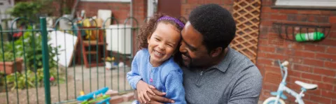 A man sitting outside, holding his daughter
