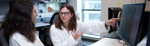 Two researchers having a discussion in front of a computer screen