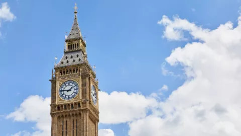 The photo shows Big Ben against a blue sky with some white clouds