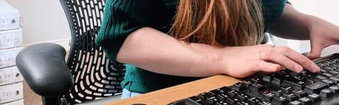 Close up of a woman's hands as she types at a keyboard